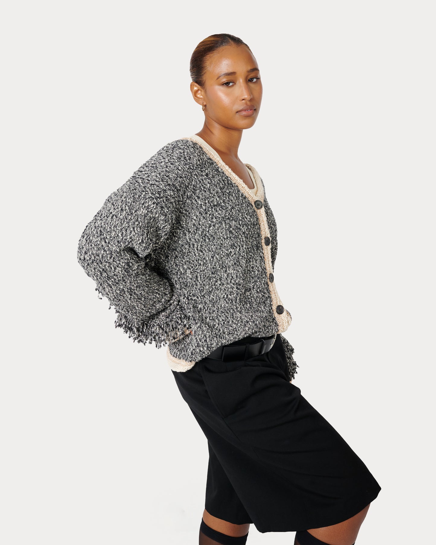 Female is wearing a size Medium in Aspen Fringe Cardigan in the black Aspen Fringe Cardigan by Aseye Studio.