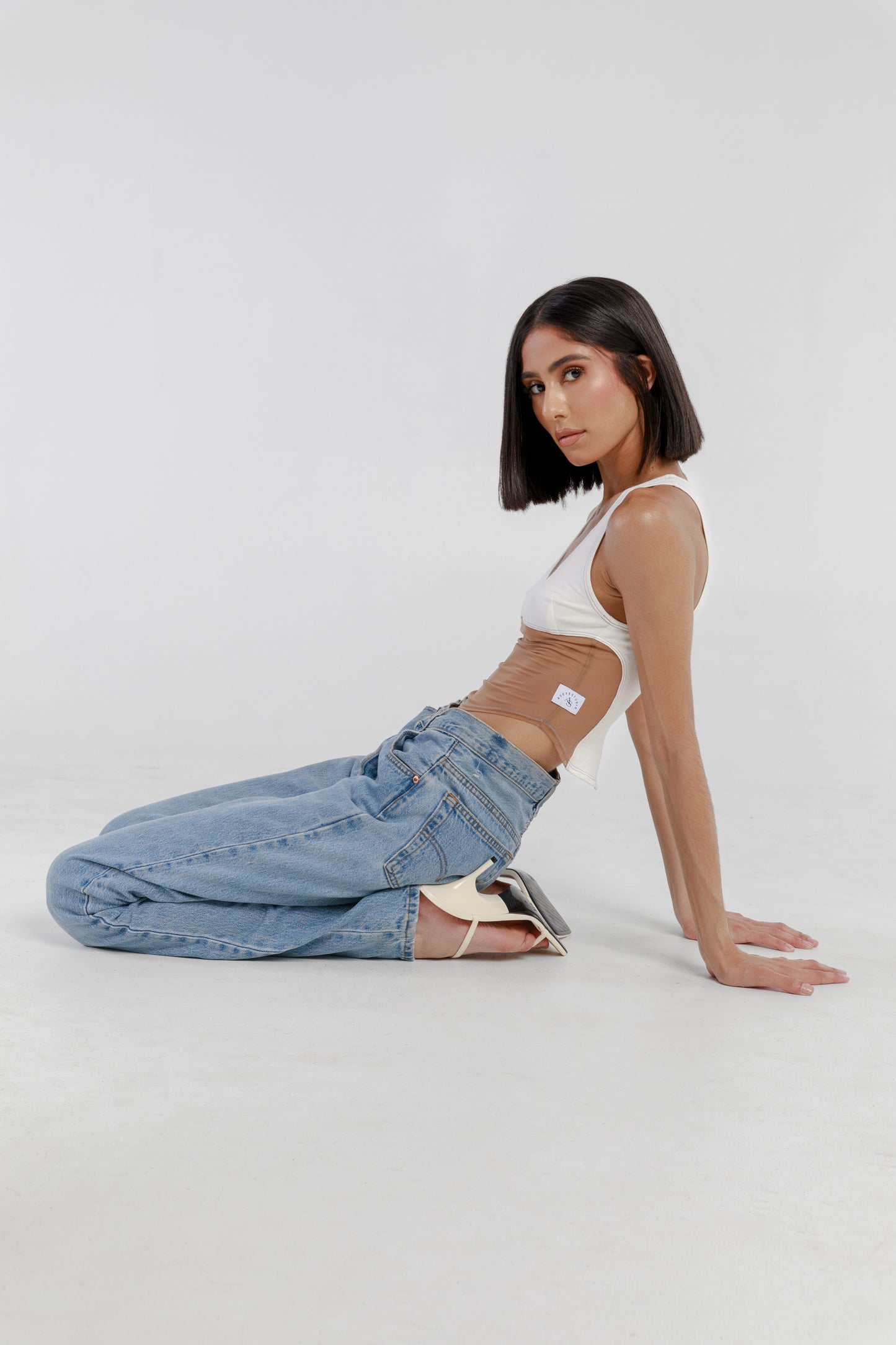 Model is wearing Kaya Mesh Tank Top in white with pearl blue and brown double-stitch seams