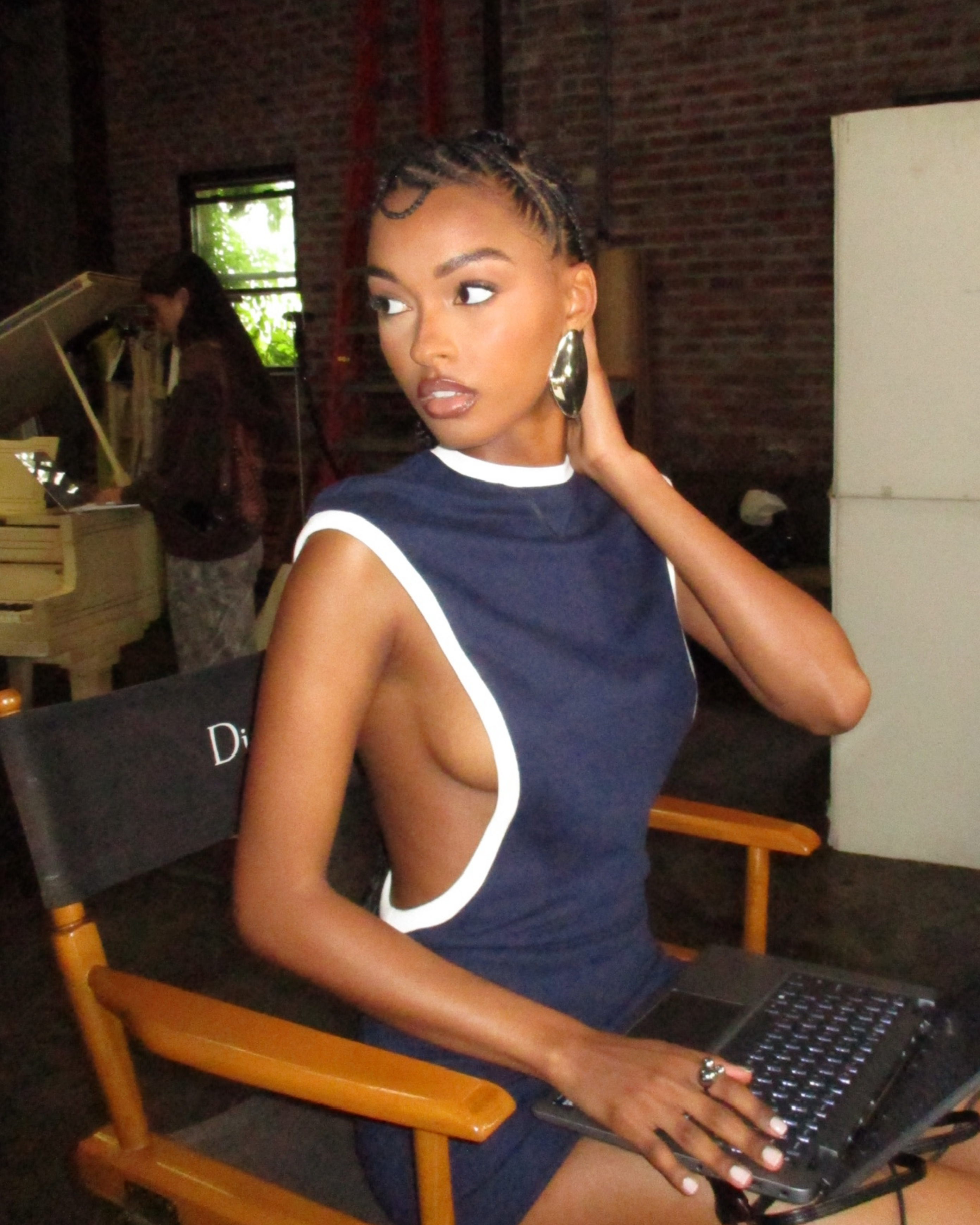 Woman in a blue and white dress sitting on a director's chair with a laptop. Discover Vacation Ready Edit by Aseye Studio