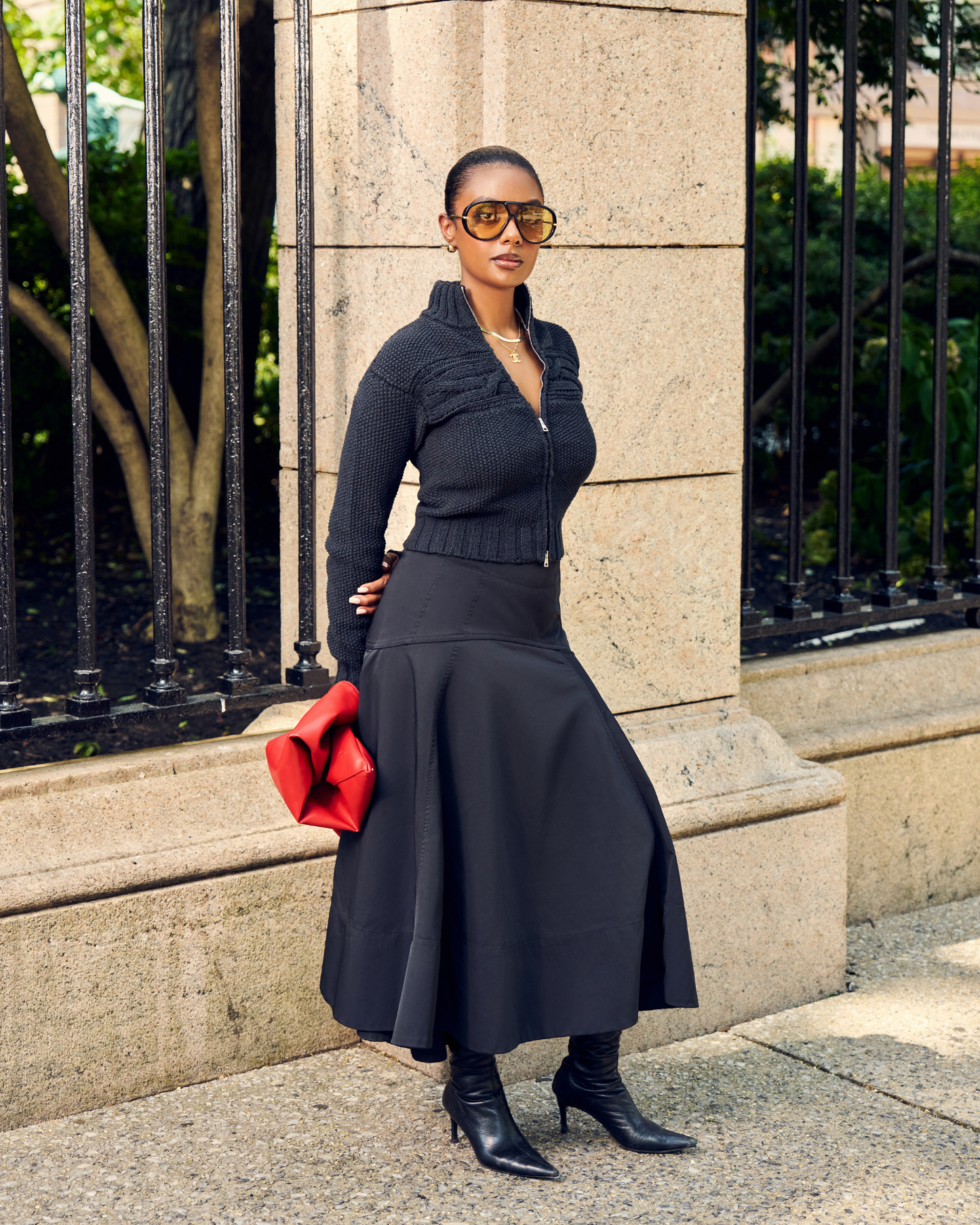 Woman in Aseye Studio Black Double-Zip Cardigan with cable knit and textured details. Paired with Black Long skirt and boots. 