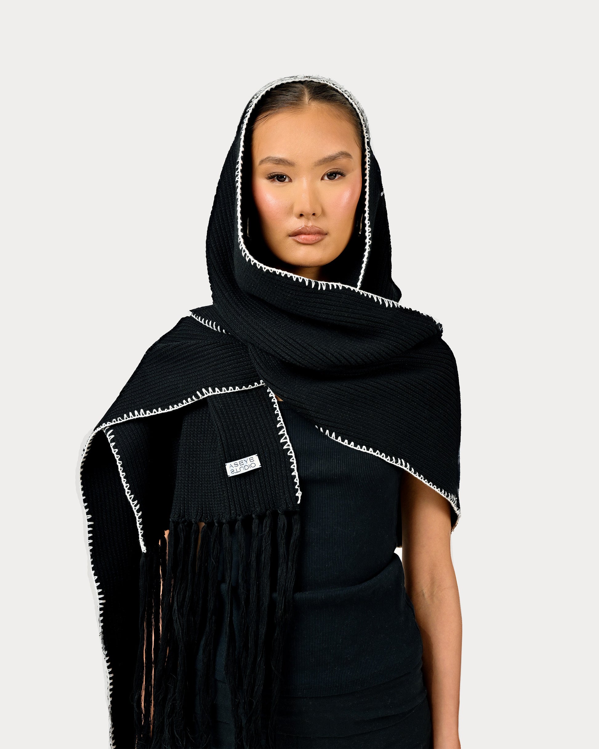 Model is wearing heavy knit Yuki Scarf by Aseye Studio in Black with white piping.