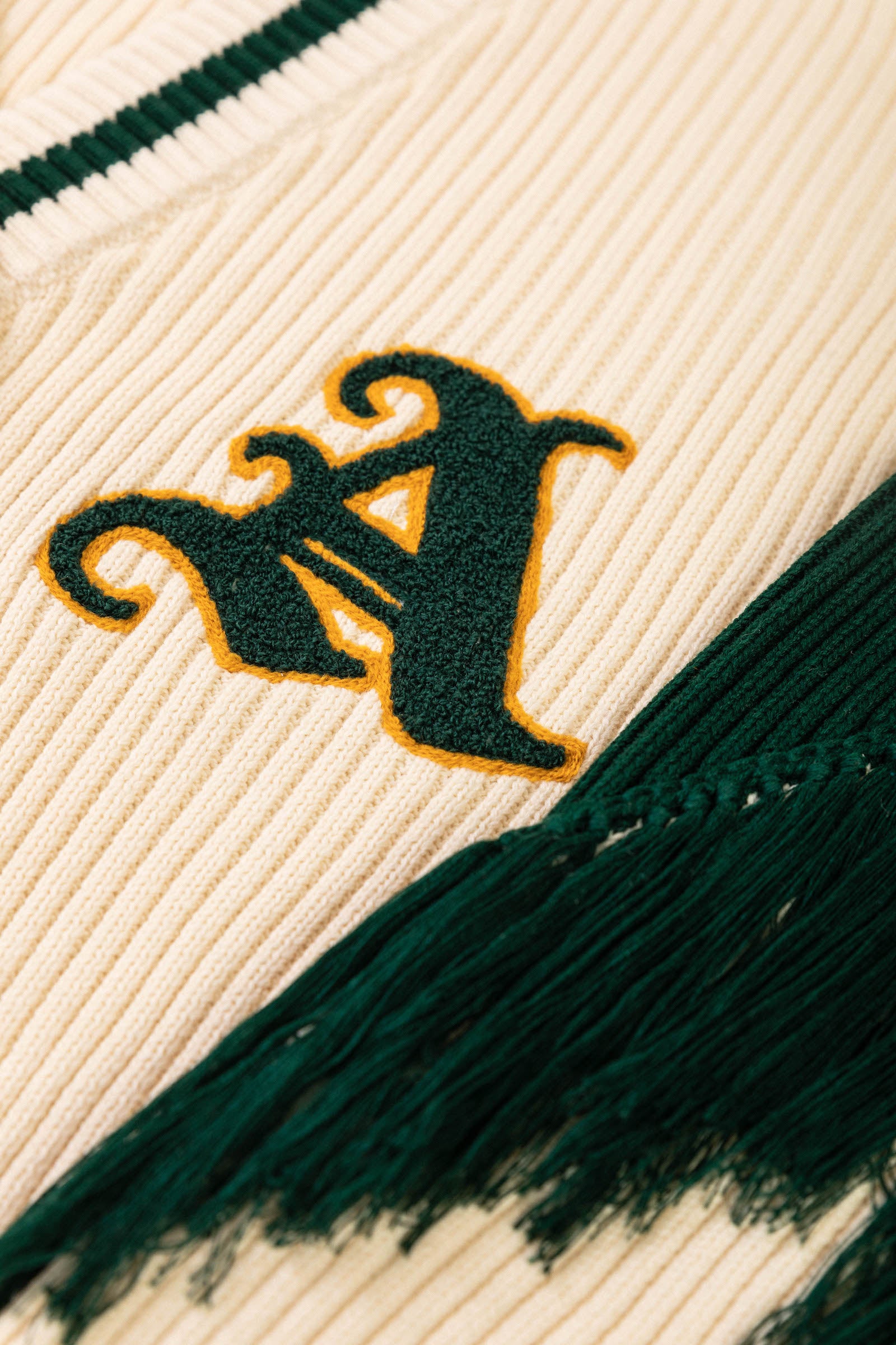 Detail View of Green Sleeve Fringes and Chenille Patch 'A' Logo in Green and Golden Yellow Outline. 